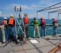 researchers on a ship doing sediment coring